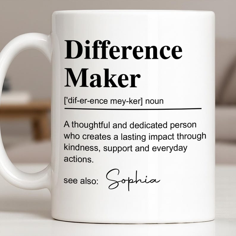 May include: A white ceramic mug featuring black printed text that defines the term Difference Maker as a thoughtful and dedicated person who creates a lasting impact through kindness, support and everyday actions, with the name Sophia listed below.