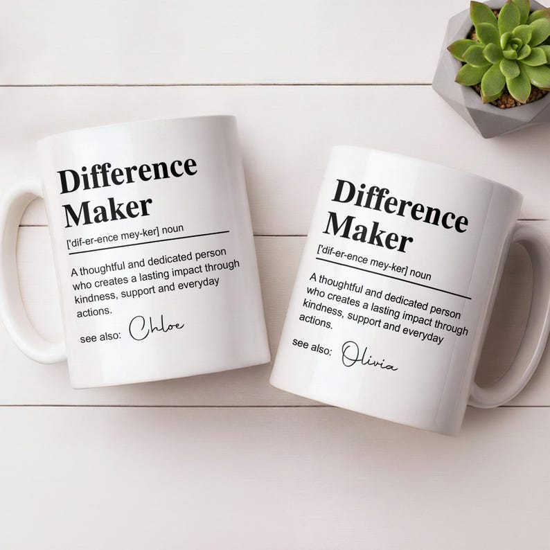 May include: Two white ceramic mugs featuring black text that defines the term Difference Maker as a thoughtful and dedicated person who creates a lasting impact through kindness, support and everyday actions, with the names Chloe and Olivia printed.