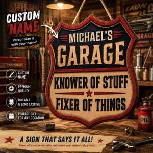 Pode incluir: Uma placa de madeira em forma de escudo com uma borda vermelha e preta apresentando o texto MICHAEL'S GARAGE, KNOWER OF STUFF e FIXER OF THINGS em letras em negrito. A placa está suspensa por uma corda e tem uma aparência texturizada.