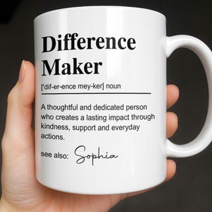 May include: A white ceramic mug featuring black printed text that defines the term Difference Maker as a thoughtful and dedicated person who creates a lasting impact through kindness, support and everyday actions, with the name Sophia listed below.