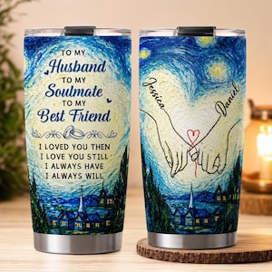 May include: Two stainless steel tumblers with a blue and yellow swirling night sky print. One tumbler features the text: TO MY HUSBAND TO MY SOULMATE TO MY BEST FRIEND I LOVED YOU THEN I LOVE YOU STILL I ALWAYS HAVE I ALWAYS WILL. The other shows two hands holding a red string with the names Jessica and Daniel.