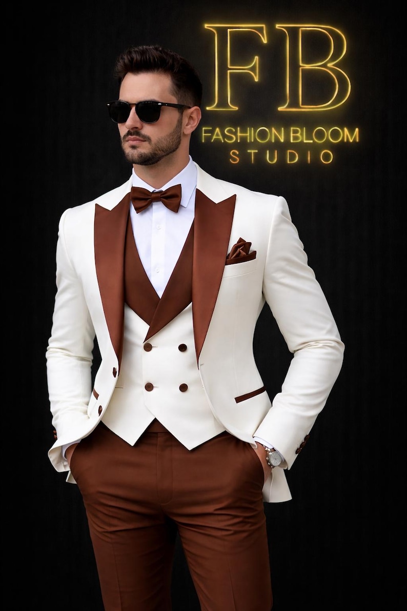 May include: A three-piece ivory suit with brown lapels, vest, and trousers. The suit features a white dress shirt, brown bow tie, and a pocket square. The image includes the text "FB FASHION BLOOM STUDIO" in a gold neon font.