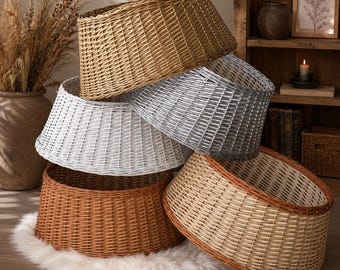 May include: A stack of five round, woven wicker tree collars in various colors including natural tan, silver-gray, white, dark brown, and a light beige with a dark brown rim. Each collar features a tapered, cylindrical shape with a woven texture.