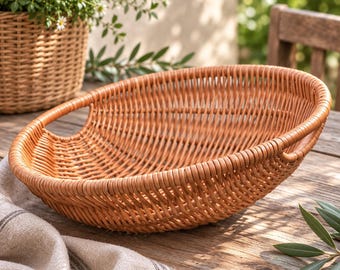 May include: A shallow, round, light brown woven basket with an open-weave design and two integrated side handles. The basket features a smooth, uniform texture and a curved, bowl-like shape, constructed from thin, flexible, natural-toned material.