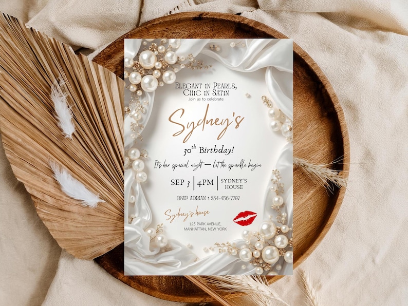 May include: An invitation for Sydney's 30th birthday, featuring elegant pearl and satin accents. The invitation includes the date, time, and location, with a red lipstick graphic. The design is set on a wooden tray with decorative elements.