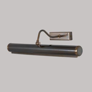 May include: A bronze-coloured picture light with a curved arm and rectangular wall mount. The cylindrical light fixture has a rounded end and a small, brass-coloured joint. The light is designed to illuminate artwork.