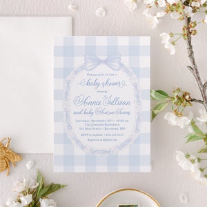 May include: A blue and white gingham baby shower invitation with a blue ribbon and a lace design. The invitation reads "Please join us for a baby shower honoring Annie Sullivan and baby Haron James".