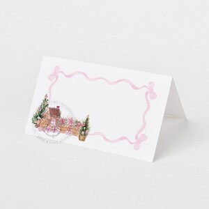 Może przedstawiać: Biała karta do miejsca z różową wstążką. Karta zawiera akwarelowy rysunek małego domu z czerwonym dachem i zielonymi drzewami.