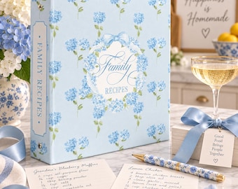 May include: A light blue three-ring binder featuring a repeating pattern of blue hydrangea flowers and a central white oval label with the text Family RECIPES. The binder spine is labeled FAMILY RECIPES and includes a matching floral pen and recipe cards.