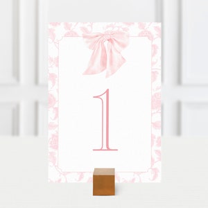 May include: Pink floral table number card with a pink bow and the number "1" printed in pink.