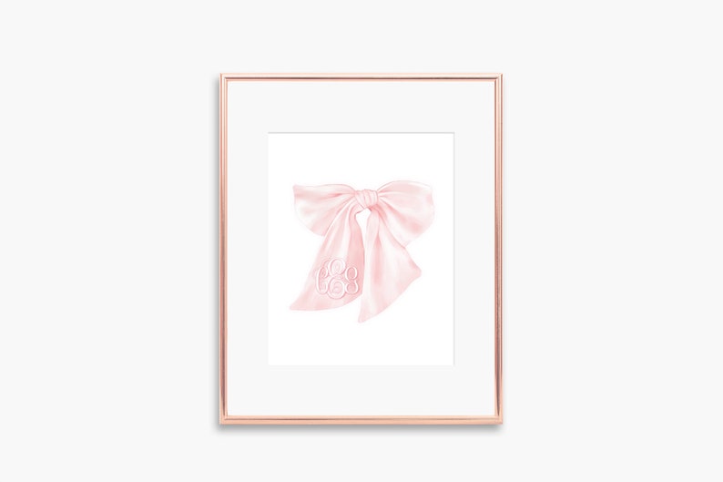 May include: A framed illustration of a pink satin bow with a white monogram in the center.