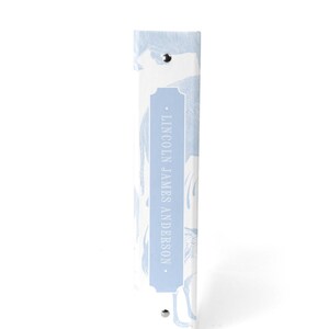 May include: A light blue binder with a white background and a pattern of stylized birds. The binder has a silver metal ring and a label that reads "LINCOLN JAMES ANDERSON."