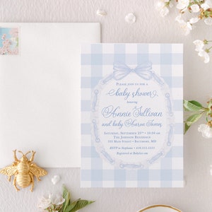 May include: A blue and white gingham baby shower invitation with a blue ribbon and a lace design. The invitation reads "Please join us for a baby shower honoring Annie Sullivan and baby Carson James".