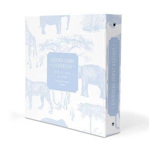 May include: A light blue baby photo album with a white background and a blue and white pattern of elephants, giraffes, and palm trees. The album has a spine with the text "LINCOLN JAMES ANDERSON." and a label on the front that reads "LINCOLN JAMES &bull; ANDERSON &bull; JULY 31, 2024 &bull; 2:54 PM &bull; 5 pounds - 3 ounces &bull; 15 inches."