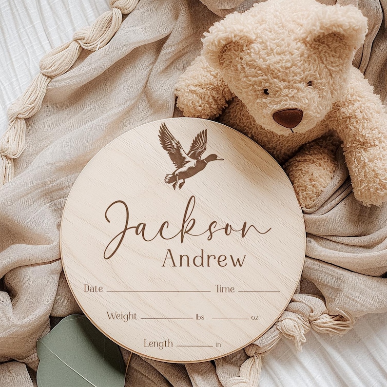 May include: A round wooden plaque with a duck silhouette and the text "Jackson Andrew" engraved on it. The plaque has spaces to record the date, time, weight in pounds and ounces, and length in inches.