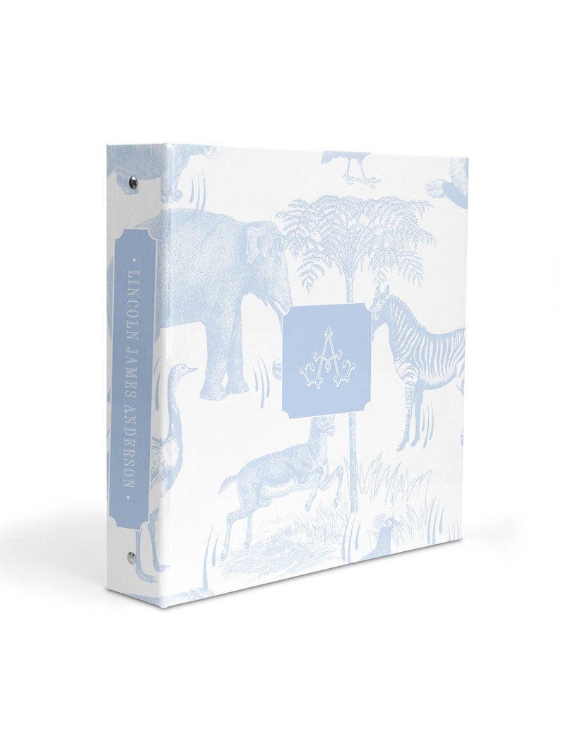 May include: A white binder with a blue and white pattern of animals, including an elephant, zebra, and a bird. The binder has a blue spine with the text "LINCOLN JAMES ANDERSON." on it. The binder also has a blue square with the letter "A" in the center.