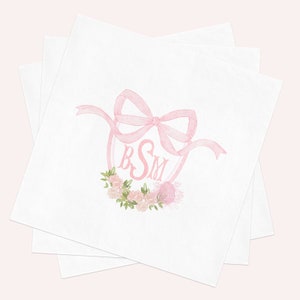 May include: A stack of white square paper napkins featuring a centered watercolor illustration of a pink ribbon bow tied above a pink monogram with the letters BSM, accented by a small cluster of pink roses and green leaves at the bottom.