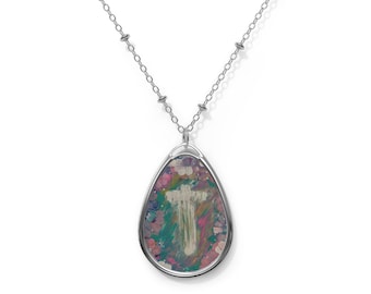 May include: A silver-toned teardrop-shaped pendant necklace featuring a central white cross design set against a vibrant, multi-coloured abstract background of pink, green, and blue brushstrokes, suspended from a delicate silver-toned chain.