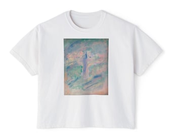 May include: A white short-sleeved t-shirt featuring a rectangular graphic print on the chest. The print displays an abstract, painterly design with blended strokes of soft pink, light blue, sage green, and lavender, forming a cross shape.