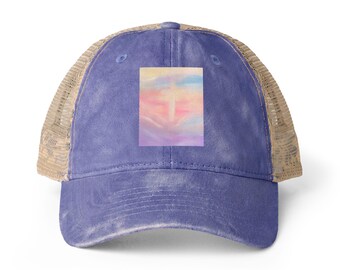 May include: A purple baseball cap with a tan mesh back and a rectangular patch on the front. The patch features a soft, blended watercolour-style design with horizontal gradients of yellow, pink, blue, and purple hues across the surface.