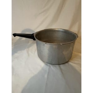 May include: A silver-colored pressure cooker with a black handle. The pot is made of metal and has a round shape. The handle is attached to the side of the pot and is made of black plastic.