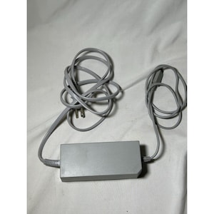 May include: A gray power adapter with a coiled cord and a two-prong plug. The rectangular adapter has a smooth surface and is connected to a second coiled cord with a connector.