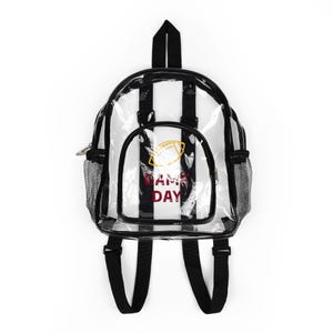 May include: Clear backpack with black and white vertical stripes. Features a front pocket with a football graphic and the words "GAME DAY" in red. Includes black shoulder straps, a top handle, and mesh side pockets.