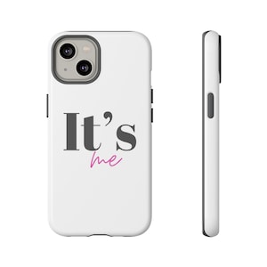 May include: White phone case featuring the text "It's me" in dark grey and pink. The phone case has a black border and a camera cutout. The phone case is shown from the front and side.