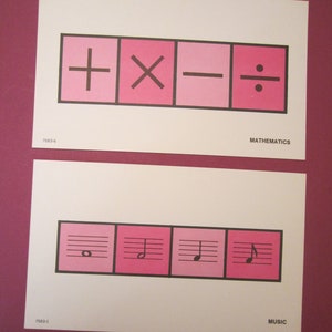 May include: Two white cards with pink and black graphics. The top card has math symbols: plus, multiply, minus, and divide. The bottom card has musical notes. The word "MATHEMATICS" and "MUSIC" are printed on the cards.