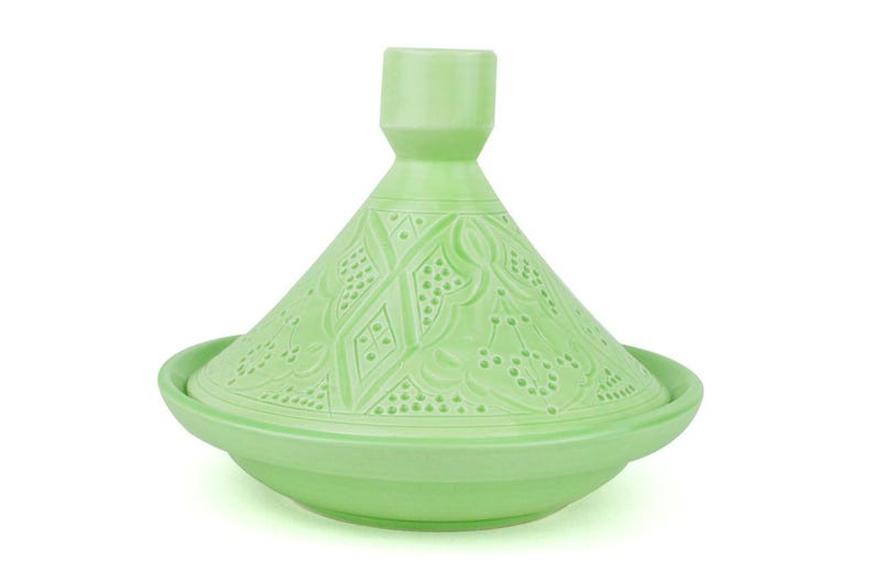 Puede incluir: Una olla de tagine de cer&aacute;mica verde claro con tapa c&oacute;nica y base redonda. La tapa presenta intrincados patrones en relieve. El tagine est&aacute; dise&ntilde;ado para cocinar y servir platos marroqu&iacute;es. La olla es de color verde claro.