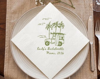May include: A white square paper napkin featuring a green ink illustration of a vintage off-road vehicle with a surfboard on the roof, palm trees, and birds. The text reads Emily's Bachelorette Miami, 2026 in a cursive and print font.