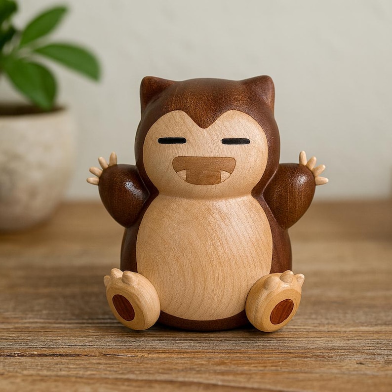 May include: A wooden figurine of a cartoon character with a brown head and limbs, and a light brown body. The figurine has closed eyes and a smiling mouth. The arms are raised, and the feet are flat on the surface.