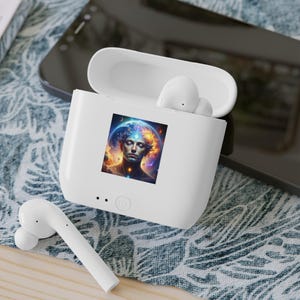 May include: White wireless earbuds and charging case. The case has a colourful graphic of a person with a celestial background. The earbuds are white and have a sleek design. The case is open, showing the earbuds inside.