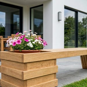 May include: A light brown wooden bench featuring a built-in square planter box on one end. The planter contains a cluster of pink, white, and purple flowers. The bench has a slatted design on the side support and a smooth, flat seating surface.