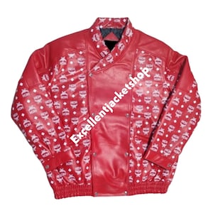 May include: A red leather jacket with a white pattern. The jacket has a unique design with a wrap-style front and silver-colored buttons. The sleeves and lower hem are ribbed. The text "Excellentjacketshop" is visible.