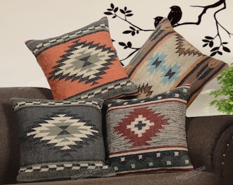 May include: Four square throw pillows featuring woven geometric patterns in shades of orange, gray, blue, brown, and red. Each pillow displays a central diamond motif surrounded by horizontal bands and checkered borders on a textured fabric surface.