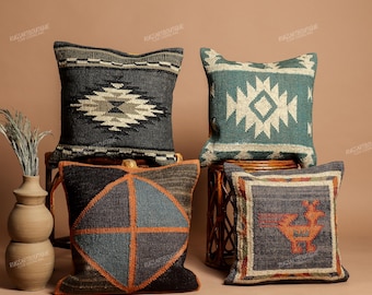May include: Four square throw pillows with woven textures. One is dark gray with a white geometric diamond, one is teal with a white diamond, one features a large orange-outlined circle divided into four, and one shows an orange bird motif.