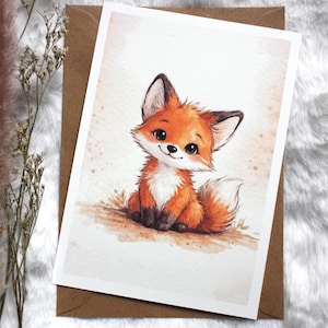 Puede incluir: Ilustración en acuarela de un lindo cachorro de zorro con pelaje naranja y blanco, sentado en un trozo de tierra. El zorro tiene ojos grandes y expresivos y una cola esponjosa. La obra de arte está sobre una tarjeta blanca, sobre un sobre marrón y un fondo blanco y esponjoso.