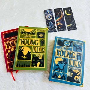 May include: A collection of illustrated books and bookmarks. The books are red, green, and blue, with the text "All The Young Dudes." The bookmarks feature celestial and clock designs. Each book has a ribbon.