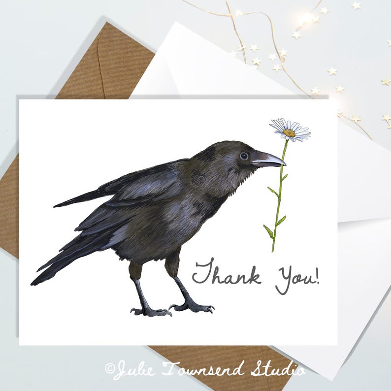 May include: A white greeting card with a detailed illustration of a black crow holding a daisy. The words "Thank You!" are written in script. The card is on a white envelope.