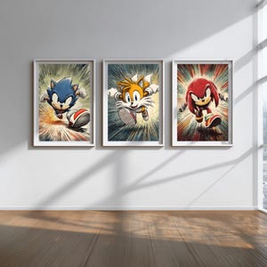 May include: Three framed art prints featuring Sonic the Hedgehog characters. The prints depict Sonic, Tails, and Knuckles in action poses against a colorful, radial burst background. Each print is in a white frame.