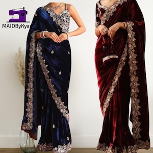 May include: Two velvet saris are shown, one in navy blue and the other in burgundy. Both have detailed gold embroidery on the edges and bodice. The navy sari has a matching embroidered top, and the burgundy one has a matching purse.