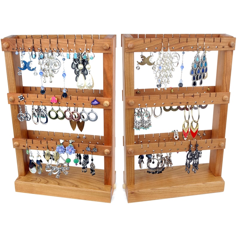 May include: A wooden earring display stand with two sections, each with four shelves. The shelves are filled with a variety of earrings, including dangle earrings, stud earrings, and hoop earrings. The stand is made of natural wood and has a rustic finish.