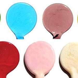 May include: Seven round glass beads in various colors, including green, blue, pink, red, brown, yellow, and white.