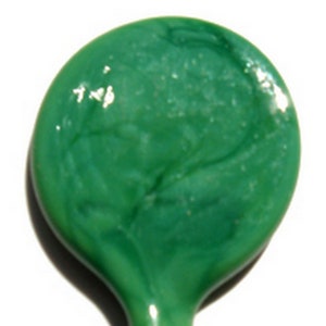 May include: A round, green glass tile with a marbled pattern. The tile has a glossy finish and a slight swirl pattern.