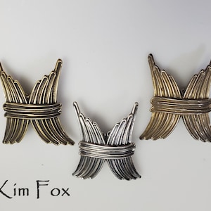 May include: Three metal butterfly-shaped charms in gold and silver. The charms are made of thin metal strips that are woven together to create a delicate and intricate design.