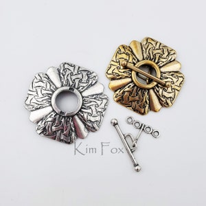 May include: Two silver and gold metal decorative clasps with a detailed design and a silver toggle clasp.