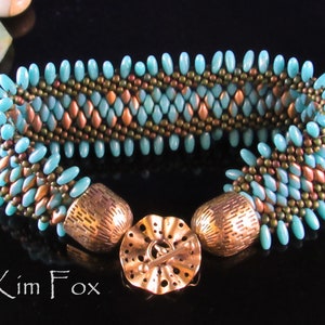 May include: A turquoise and copper beaded bracelet with a decorative clasp. The bracelet is made with seed beads and features a chevron pattern.