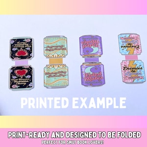 May include: Print-ready paper cutouts of fantasy-themed soda cans. Each can features unique designs and text, including "Dark Romance Forbidden Cherry," "Fantasy Fling Potion Pop," "Fated Mates," and "Enemies to Lovers." The text "PRINTED EXAMPLE" is also visible.