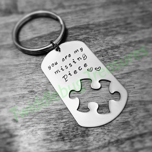 May include: Silver keychain with a puzzle piece cutout and the text "You are my missing piece" with two small hearts.